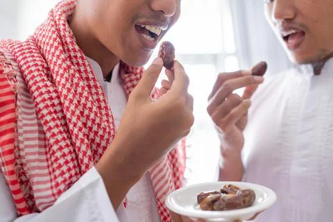 Muslim sharing a bowl of dates while enjoying iftar dinner together Stock Photos