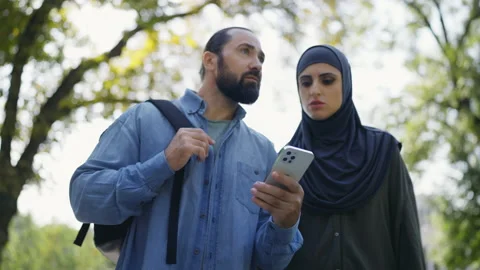 Muslim tourist couple using navigation on smartphone to travel, vacation Stock Footage 219877087