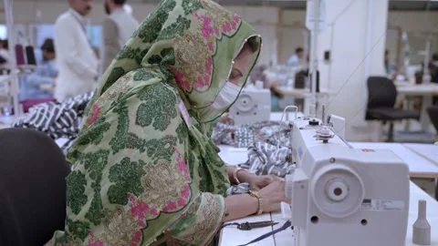 Muslim woman sewing cloth while wearing protective face masks working at factory Stock Footage