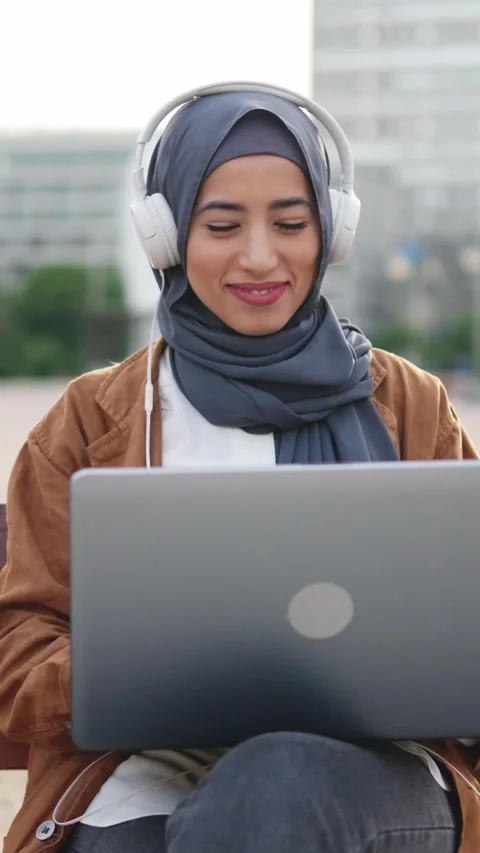 Muslim woman using a laptop while sitting on a square Stock Footage 239907421