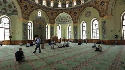 Muslims pray in a huge beautiful mosque. Men are sitting on the floor in Mosque Stock Footage 122299853