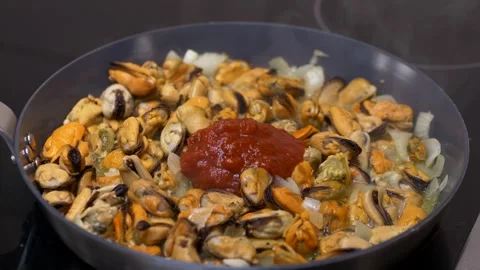 Mussels cooked inside hot sauce pan, cook adds tomato sauce, steam lifting above Stock Footage 321818357