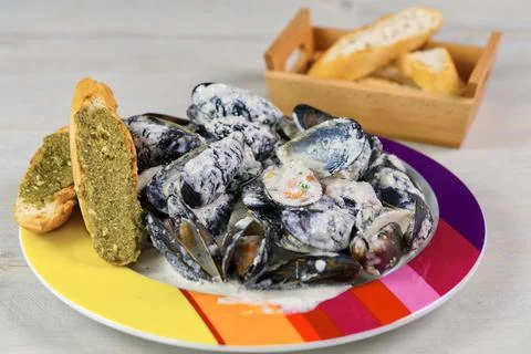Mussels in a creamy sauce on a plate with chebata with pesta sauce. Stock Photos