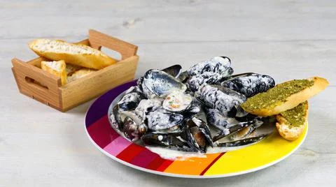 Mussels in a creamy sauce on a plate with chebata with pesta sauce. Stock Photos
