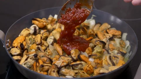 Mussels heating inside hot pan as chef adds rich tomato sauce, rising steam Stock Footage 321819642