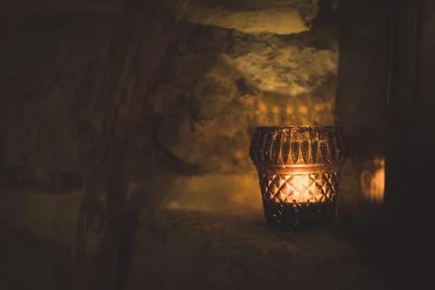 Muted horizontal shot of tea light candle on rock wall with wooden frame Stock Photos