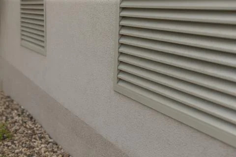 Muted tones of stucco wall with linear design elements and vents Fotos de archivo