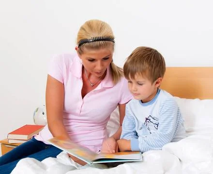  Mutter mit Kind im Bett beim Geschichten vorlesen. Eine Mutter mit Kind i... Stock Photos