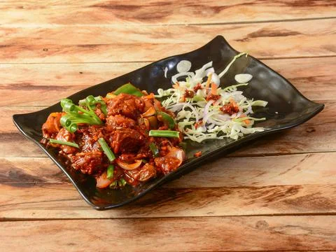 Mutton chilli or Lamb chilli, spicy and delicious dish served over a rustic w Stock Photos