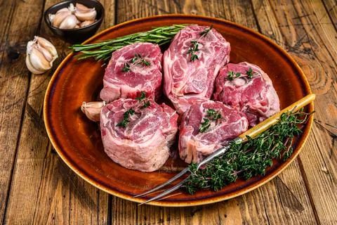 Mutton lamb neck meat on a rustic plate with thyme and rosemary. wooden Stock Photos