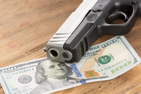 Muzzle of a gun with a 100 dollar bill Stock Photos