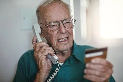 My card number is...a senior man reading something off his credit card while Stock Photos