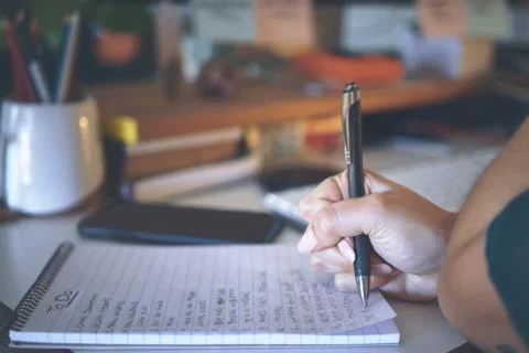 My to-do list keeps growing. an unrecognizable woman sitting alone and writing Stock Photos