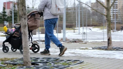 My father drives a stroller through the snow at the beginning of winter Stock Footage 271676127