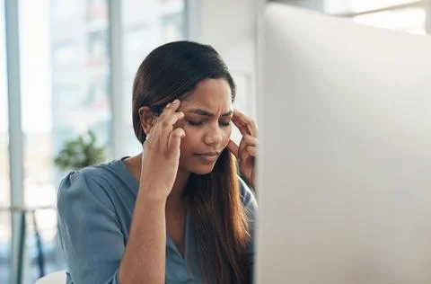 My head is about to explode. a young businesswoman experiencing a headache while Foto stock
