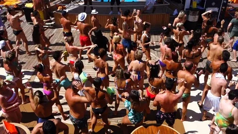 Mykonos: crowd of passengers dancing during a pool party on board a cruise ship Stockbeeldmateriaal 129824294