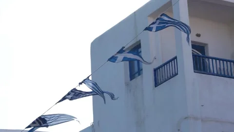 Mykonos, Greece Close Up Slow Motion Line of Flags Blow in the Wind In Fron.. Vídeo Stock 336511949