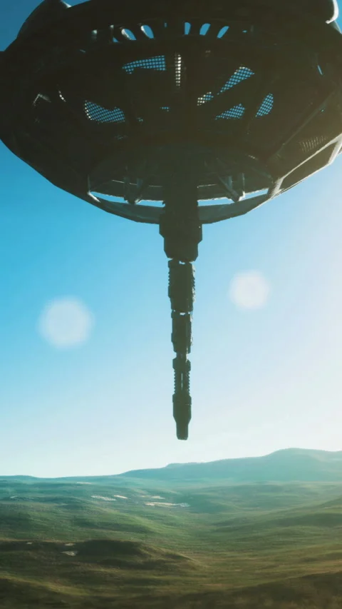 Mysterious alien ship hovering over lush landscape under a clear blue sky Stock Footage 324498615