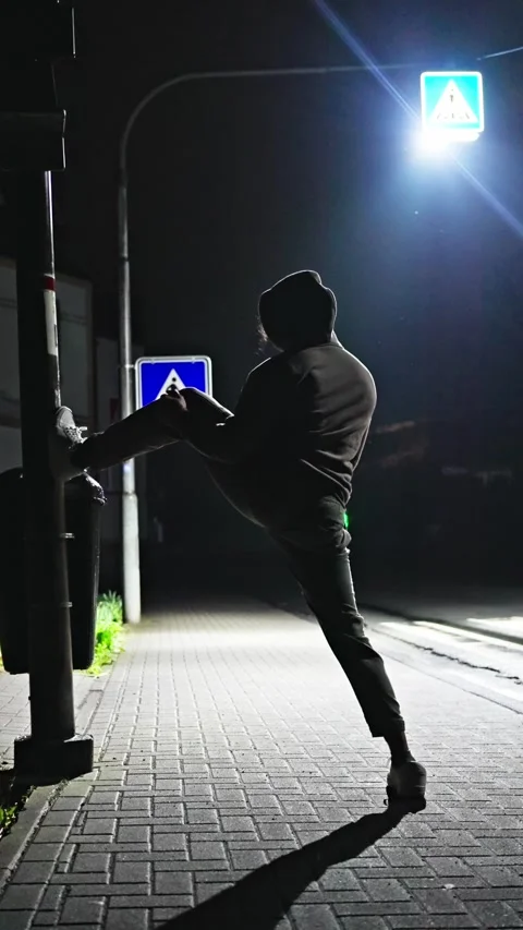 A mysterious and ghostly figure elegantly stretches and exercises under a street Stock Footage 307125376