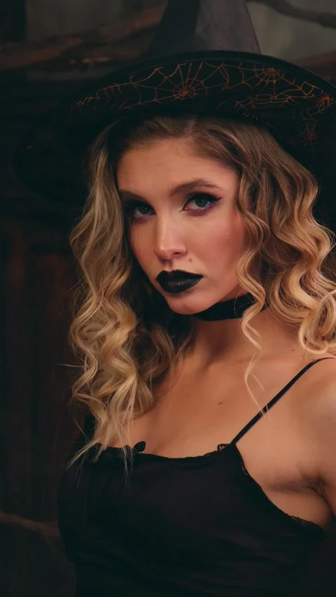 Mysterious blonde witch in a pointed hat and black lipstick slowly turns to the 스톡 동영상 342068469