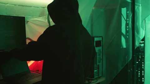 Mysterious cyber security hacker in hoodie in headquarter with computer screens Stock Footage 245484663