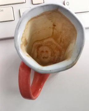 Mysterious Face of Death Revealed inside a Coffee Mug on Office Desk Foto stock