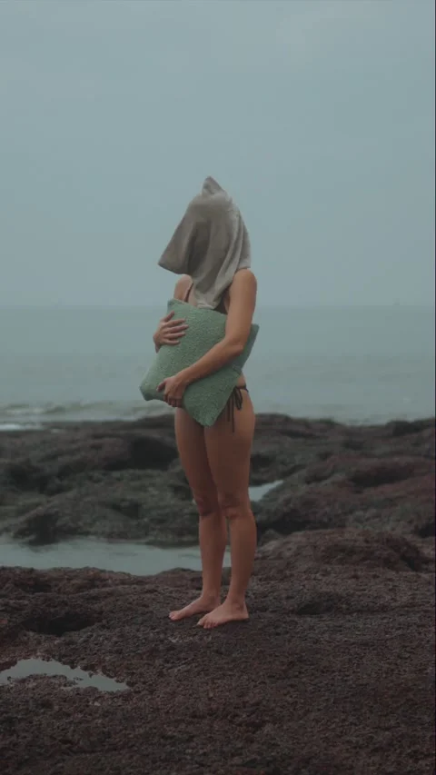 Mysterious Figure with Covered Head on Rocky Ocean Shore Stock Footage 328809953