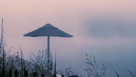 Mysterious fog gradually enveloping a beach parasol by the sea Stock-Footage 288242554