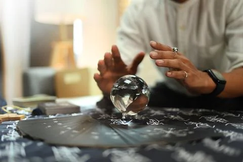 Mysterious fortune teller predicting future with crystal ball on desk 写真素材