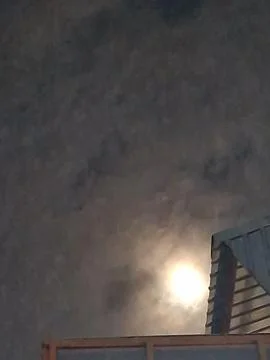 Mysterious full moon glowing through dark night clouds Foto stock