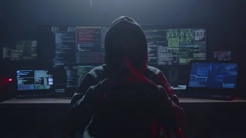 A Mysterious Hacker sits in a Dark Room Surrounded by Multiple Computers Stock Footage 281759562