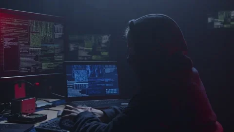 A Mysterious Hacker is sitting in a Dark Room, Surrounded by Multiple Screens Stock Footage 281759724