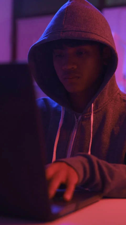 A mysterious hooded hacker working on a computer in a dark room. Stock Footage 331989697
