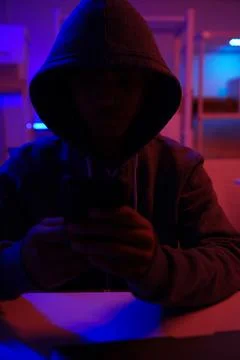 A mysterious hooded hacker working on a computer in a dark room. Stock-Fotos