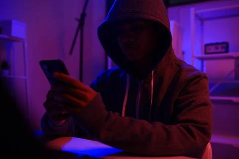 A mysterious hooded hacker working on a computer in a dark room. Stock-Fotos