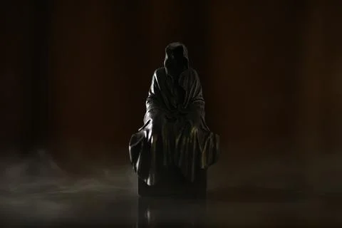 Mysterious Hooded Statue in Dark Dramatic Lighting Stock Photos