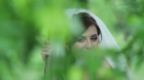 Mysterious image of the bride against the background of green foliage Stock Footage 32475801
