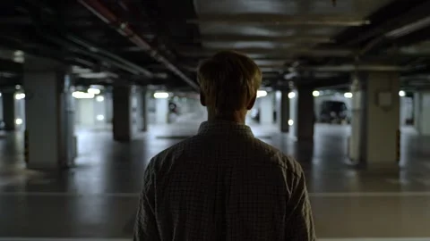 Mysterious man walking alone in an empty parking garage Stock Footage 320255489