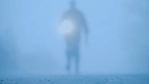 Mysterious silhouette walking towards camera with flashlight in thick fog a.. Stock Footage 334557503