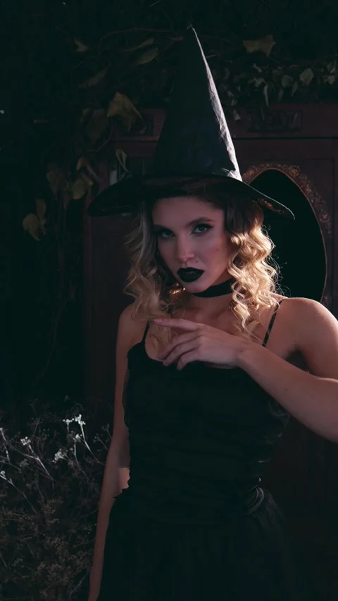 Mysterious witch with dark makeup and pointed hat in a black dress posing Stock-Footage 342068123