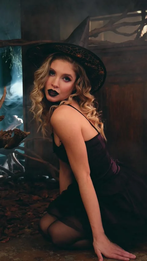 Mysterious young witch with dark makeup and a pointed hat kneeling on the ground Stock-Footage 342068407