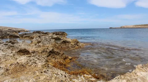 Mystical-Low Level Shot, Sandy Rocky Rocks With Slow Waves Moving With Blue Sky Vidéo 34256062