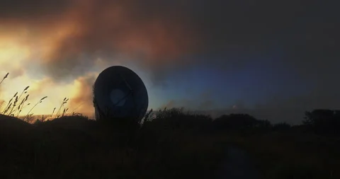 Mystical sunset sky with dark clouds shadowing a parabolic reflector - pan Video stock 159456406