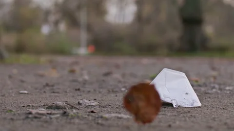 N95 mask laying on the ground, leaf flying - Coronavirus Covid-19 Epidemic Stock Footage 165676771