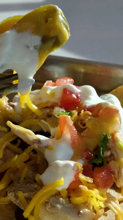 Nachos cheese toppings Scooping Loaded Nachos Cheese Topping with Tortilla Chip Stock-Footage 314098066