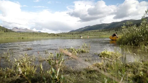 Nahanni river with rafters through an open field Stock Footage 92366621