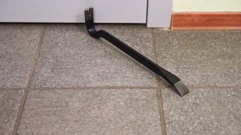 Nail crowbar crashes onto tiled floor in empty workshop premise Stock Footage 276023680