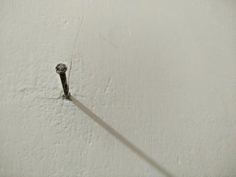 A nail embedded in the white cement wall 库存照片