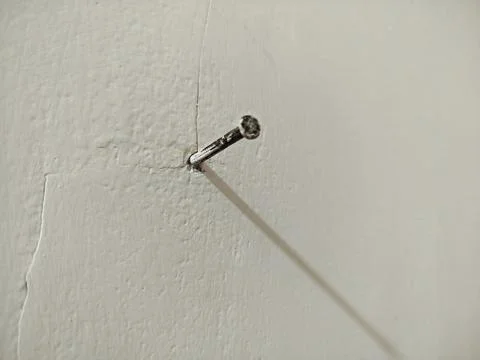 A nail embedded in the white cement wall 스톡 사진
