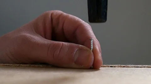 A nail is hammered in a flat pack in slow motion Stock Footage 98663316